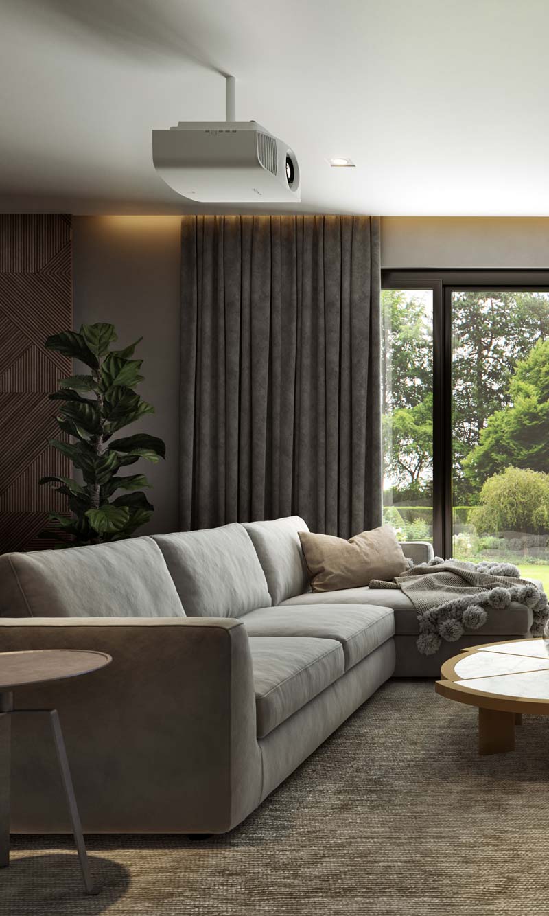 White home theater projector mounted on the ceiling above a grey sectional sofa