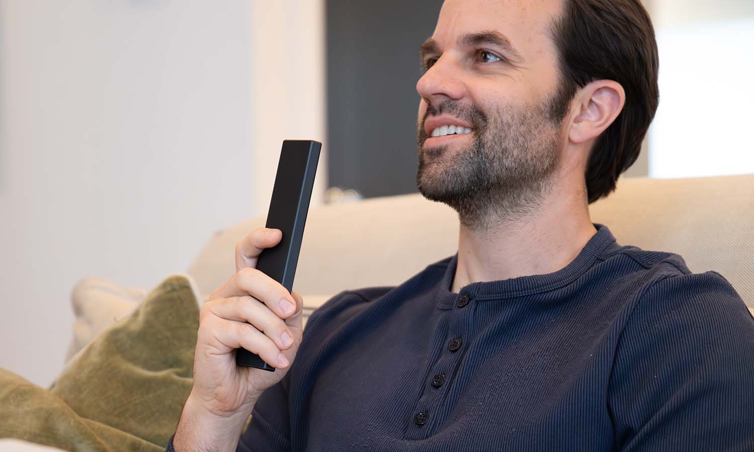Man smiling while holding a slim black remote control