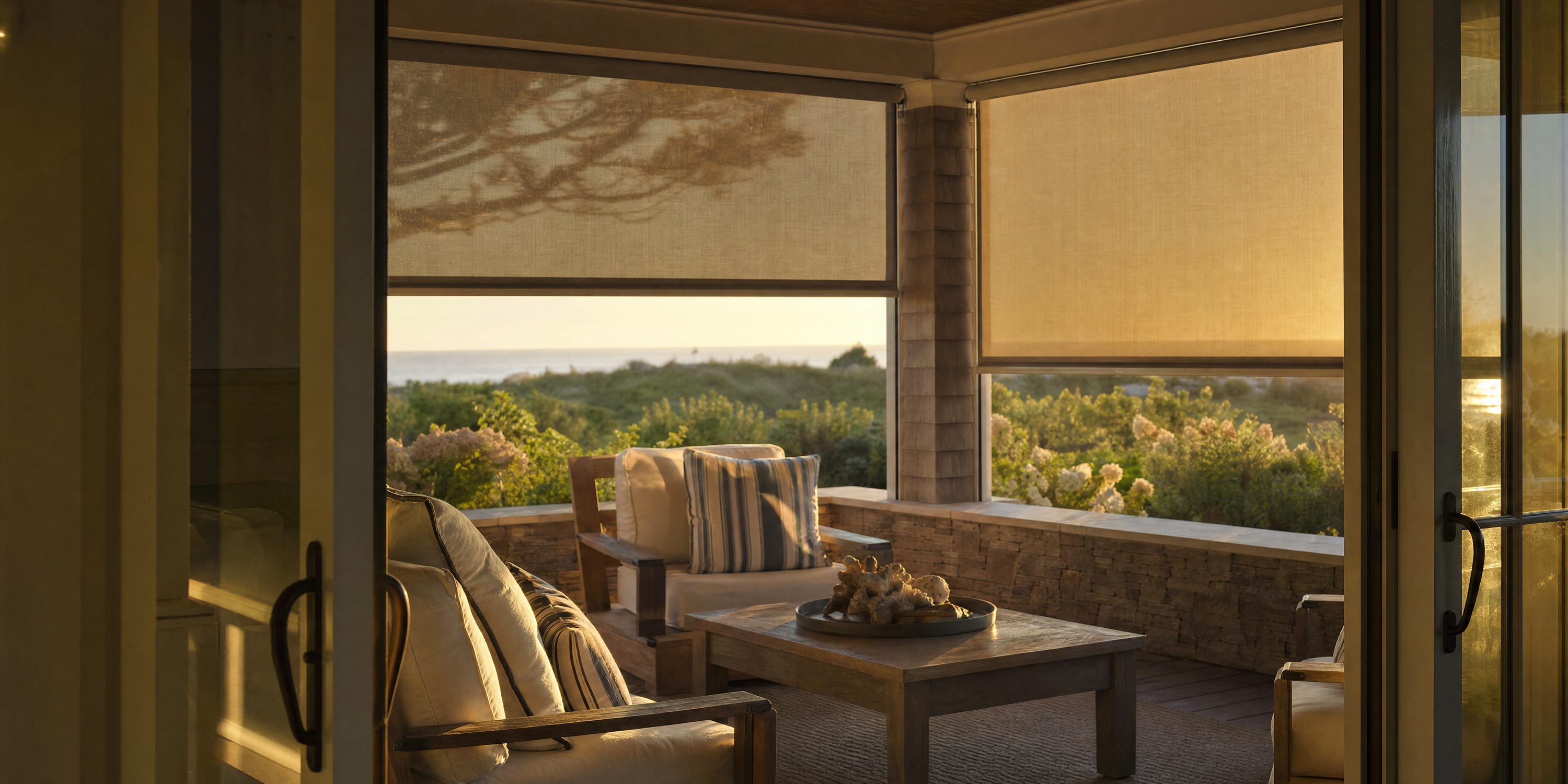 Covered porch with outdoor seating and motorized sun shades partially lowered
