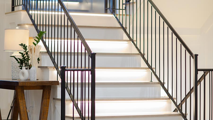 Modern staircase with illuminated white steps and black metal railings