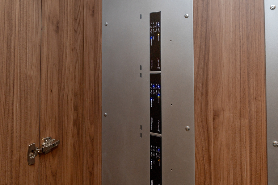 Control4 equipment rack mounted in a wood-paneled closet with labeled AV components