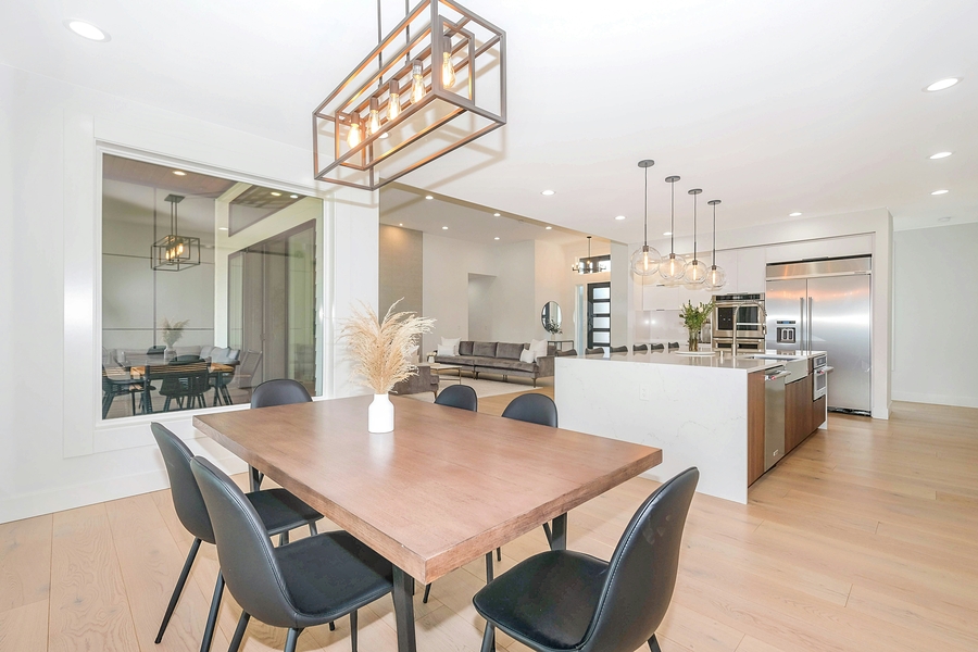 Layered luxury lighting design in an open-concept dining and kitchen space with a geometric chandelier and pendant lighting