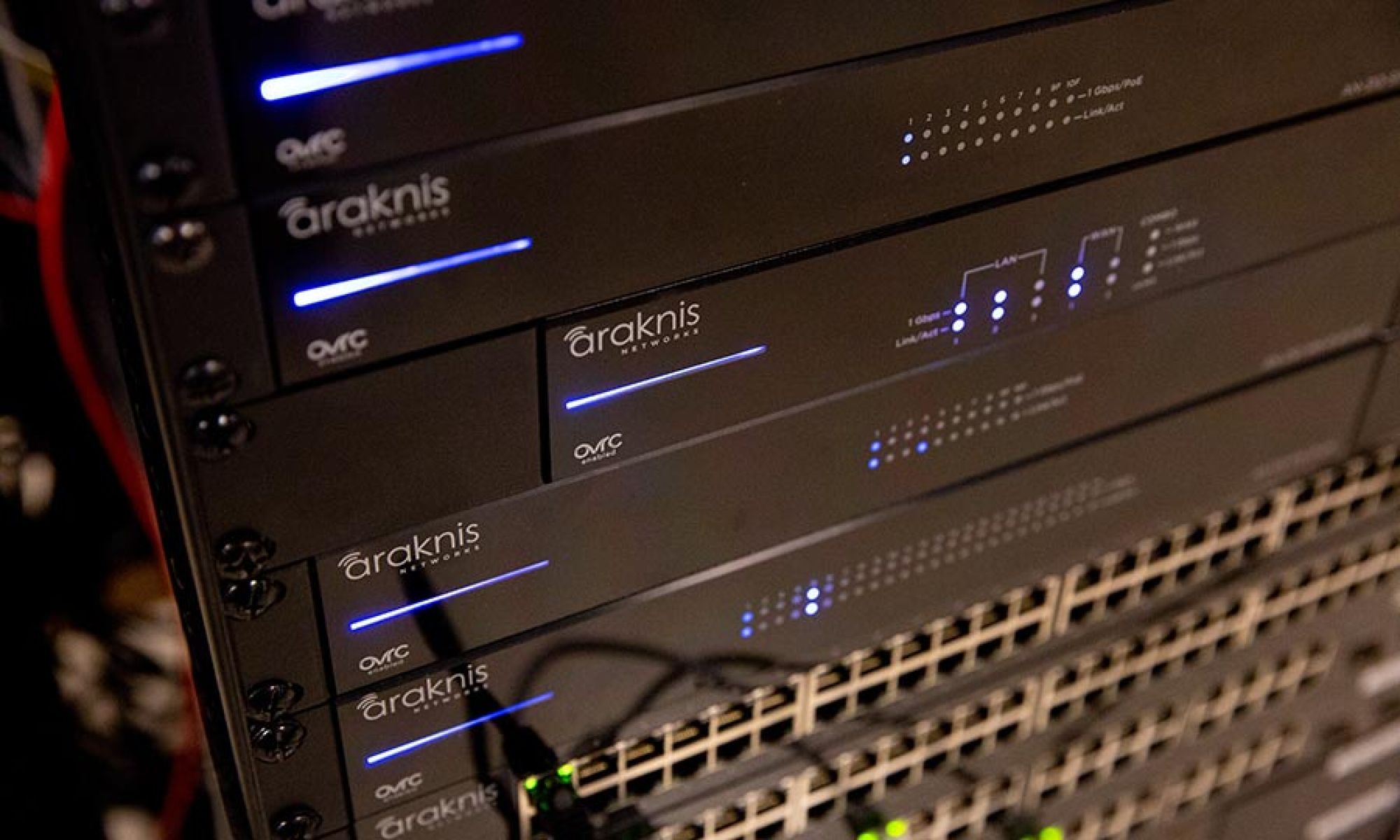 Network switches and routers stacked in a server rack with blue indicator lights