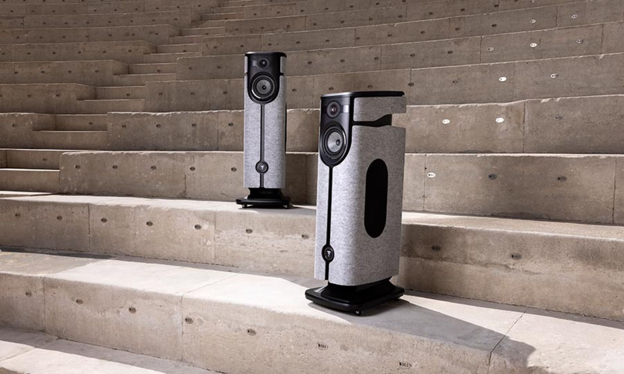 Pair of high-end gray fabric and black floor-standing speakers on concrete steps
