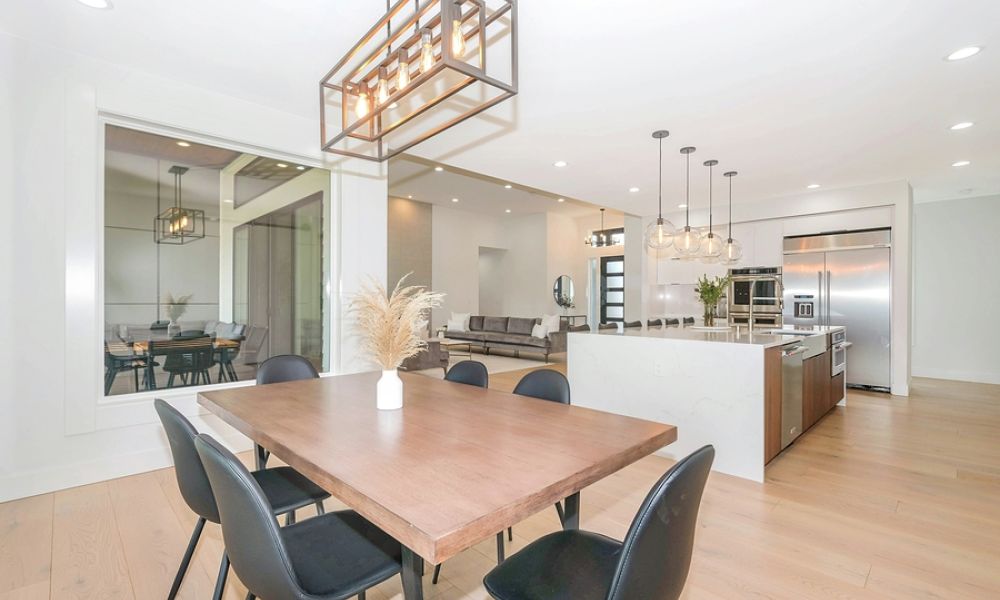 Layered luxury lighting design in an open-concept dining and kitchen space with a geometric chandelier and pendant lighting